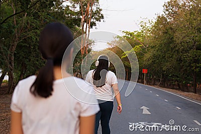 Overweight woman listen to music while walking in the park. Editorial Stock Photo