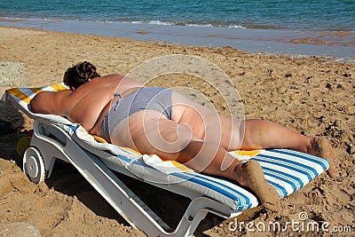 Overweight woman sunbathe on beach Stock Photo