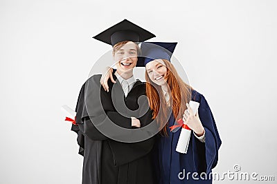 Overwhelmed couple of university graduates happy to receive their diplomas, smiling at camera, redhead girl and boy with Stock Photo