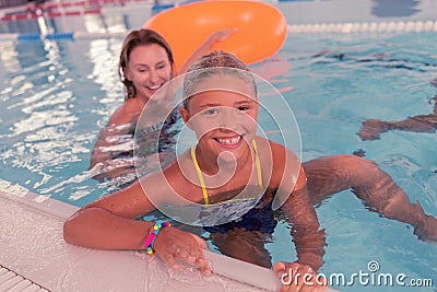 Cheerful joyful girl holding the edge of the pool Stock Photo