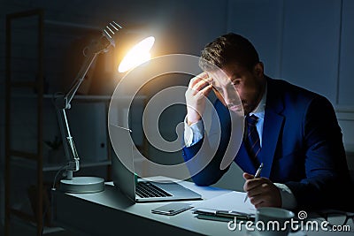 Overwork. Businessman working with laptop and writing report Stock Photo