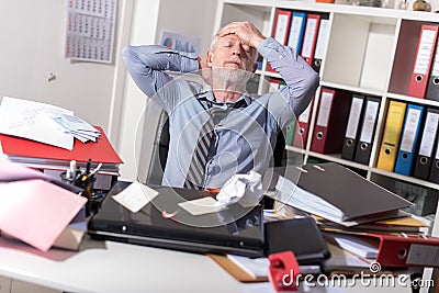 Overworked businessman sitting at a messy desk Stock Photo