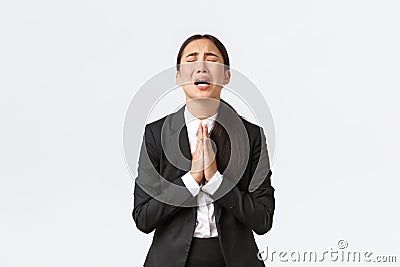 Overworked and distressed asian businesswoman begging for help, screaming hold hands together, pleading and crying Stock Photo