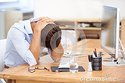 Overworked and exhuasted. an overworked businessman hunched over his desk in front of his computer. Stock Photo