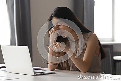 Overworked stressed asian business woman holding glasses feeling eye strain Stock Photo