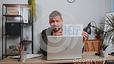 Overworked tired freelance businessman working on laptop showing inscription notebook with Help text Stock Photo