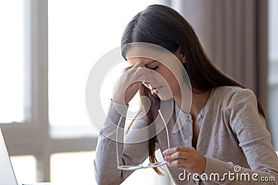 Overworked tired young woman student holding glasses feeling eye strain Stock Photo