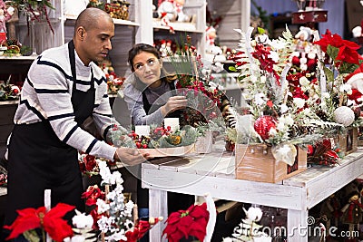 Owner and assistant of a flower shop prepares christmas decorations and arrangements Stock Photo