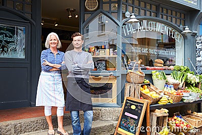 Owners Standing Next To Produce Display At Deli Editorial Stock Photo