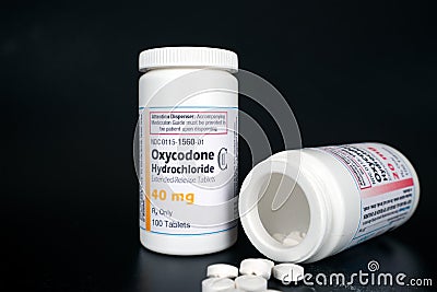 Oxycodone Hydrochloride prescription bottles isolated on black background, pills laying infront of bottles. Editorial Stock Photo