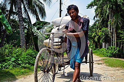 Poor young man pulling heavy-loaded metal van. A rickshaw van puller working hard to carry the load in the van. Editorial Stock Photo