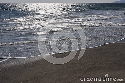 Pacific ocean with glistening sun on the sand Stock Photo