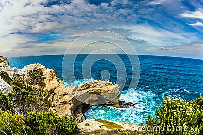 Pacific ocean waves crash down on the shore. Coastal rocks formed a picturesque arch of sandstone. Great Ocean Road of Australia. Stock Photo