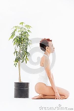 Pacified african american young woman near small tree in pot Stock Photo