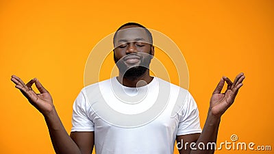 Pacified black man meditating against yellow background, breathing exercises Stock Photo