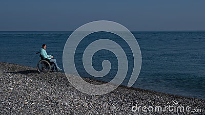 Pacified caucasian woman in a wheelchair on the seashore. Stock Photo