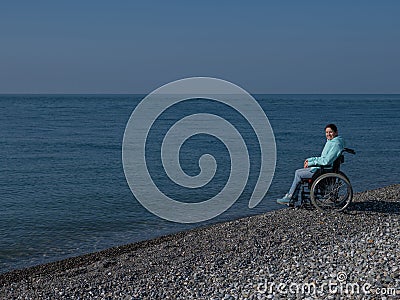 Pacified caucasian woman in a wheelchair on the seashore. Stock Photo