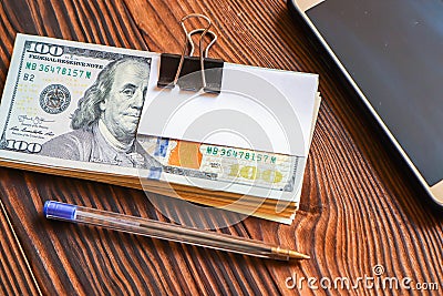 Pack of dollars phone pen and paper sticker for your text on wooden background Stock Photo