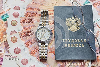 On a pack of five thousandth bills there is a work book, a watch and glasses Stock Photo