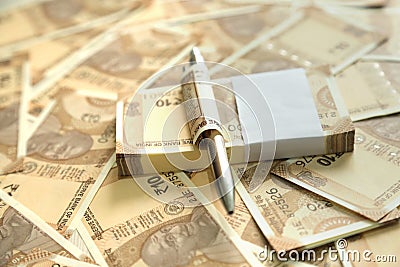 Pack of Indian 10 rupee currency note with pen and scattered Indian currency notes Stock Photo