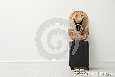 Packed suitcase, shoes and summer accessories near white wall indoors. Space for text Stock Photo