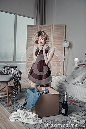 Woman feeling sentimental packing clothes of ex in the bedroom Stock Photo