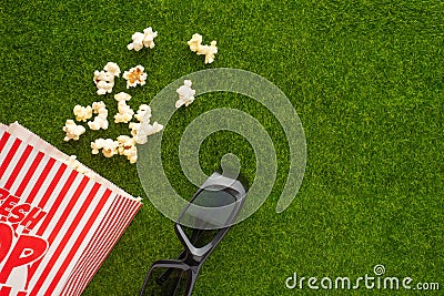 Packing with popcorn on a green lawn with 3D glasses for watching a movie. Grass Watching films about nature. In parks. Recreation Stock Photo