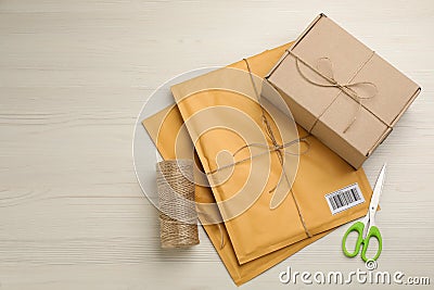 Padded envelopes, box, rope and scissors on white background, flat lay. Space for text Stock Photo