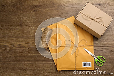 Padded envelopes, box, rope and scissors on wooden background, flat lay Stock Photo