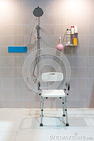 Padded shower chair with arms and back in bathroom with bright t Stock Photo