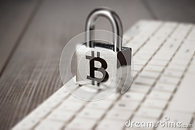 Padlock with bitcoin symbol and white computer keyboard on the wooden office table. blockchain technology concept Stock Photo
