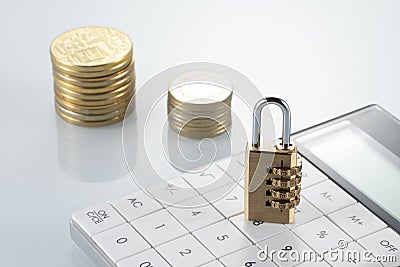 Padlock on a calculator with coins in the background Stock Photo