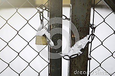 Padlock and chain snowy at the metal fence. Real estate and security Stock Photo