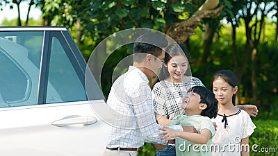 Padre asiatico che tiene suo figlio fuori dall'automobile con la madre & la figlia accanto archivi video Padre asiatico che tiene suo figlio fuori dall'automobile con la madre & la figlia accanto archivi video