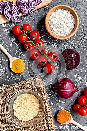 Paella home cooking with rice, tomato, onion and spices for ingredients on dark background top view Stock Photo