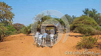 A game vehicle stuck in loose sand being pushed by passengers Editorial Stock Photo