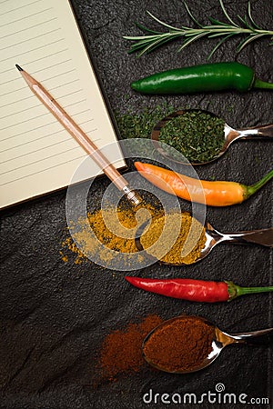 Page of notebook for recipe and pencil and oriental spices in spoons peppers on the black metallic tray in Asian style Stock Photo