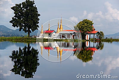 Pagoda with red rooftops and golden spires in the mirroring in Lake Inle, Myanmar/Burma Stock Photo