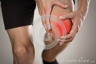 Pain in the knee of a man. Highlighted in red. On a gray background. Close up Stock Photo