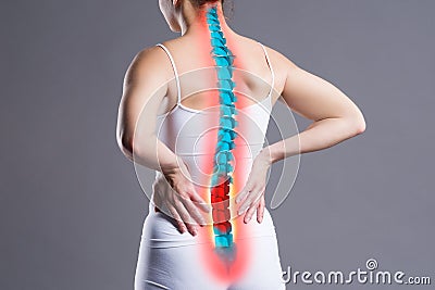 Pain in the spine, woman with backache on gray background, back injury Stock Photo
