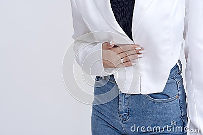 A pained woman leaning slightly forward while holding her stomach in agony. Isolated on a white background Stock Photo