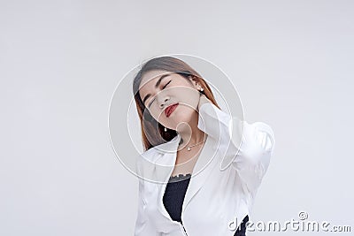 A pained young woman with tilted head holding her stiffed neck in pain. Isolated on a white background Stock Photo