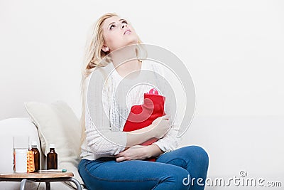 Woman feeling stomach cramps sitting on cofa Stock Photo