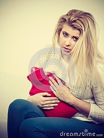 Woman feeling stomach cramps sitting on cofa Stock Photo