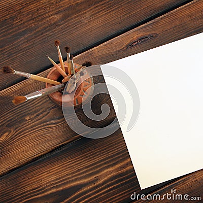 Paint brushes and paper on wooden background. Stock Photo