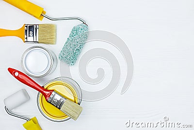 Paint cans, brushes, paint rollers on white wooden desk surface Stock Photo