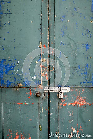 Paint flaking off a disused locked up door with padlock and grungey colors Stock Photo