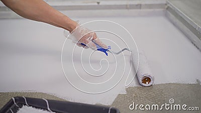 Contract painter painting garage floor to speed up selling of home. Paint the floor with a roller Stock Photo