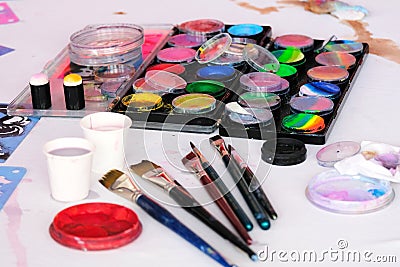 Paint palettes and brushes being used on an artist workshop table. Stock Photo