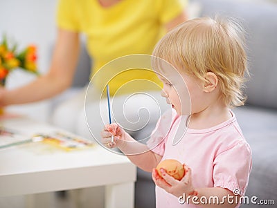 Paint smeared baby coloring Easter egg Stock Photo